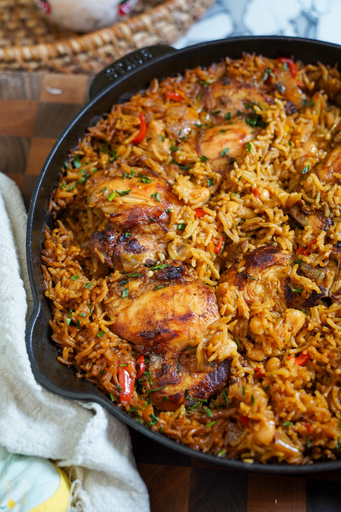 Close-up of one-pot honey garlic chicken with cannellini beans and basmati rice, cooked in a cast iron skillet. Juicy chicken thighs are nestled in fluffy, golden rice and tender white beans, garnished with fresh herbs.